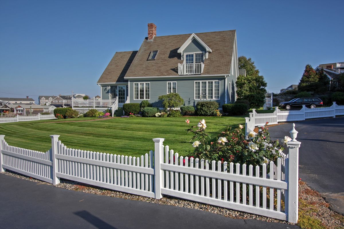 Decorative wood picket fence bordering a front yard